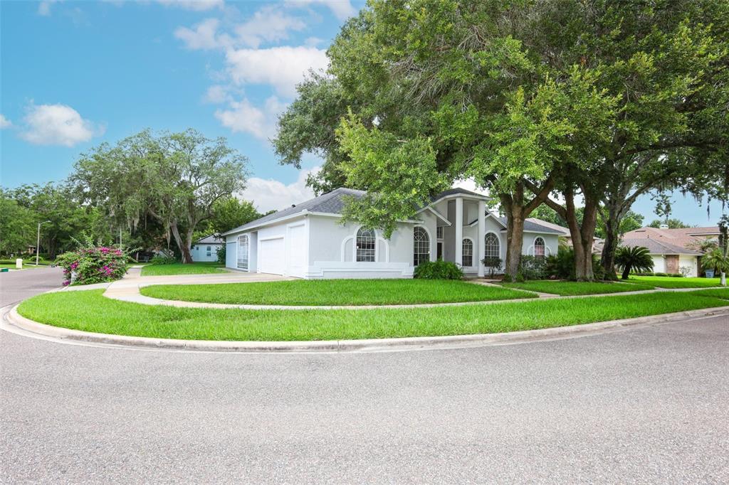A single-story house with a white exterior, arched windows, and a large tree in front — 2357 CHANTILLY TERRACE, OVIEDO, FL