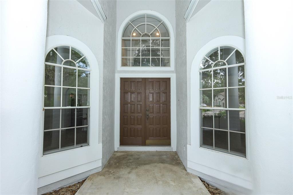 A front entryway features a double door flanked by two tall arched windows — 2357 CHANTILLY TERRACE, OVIEDO, FL