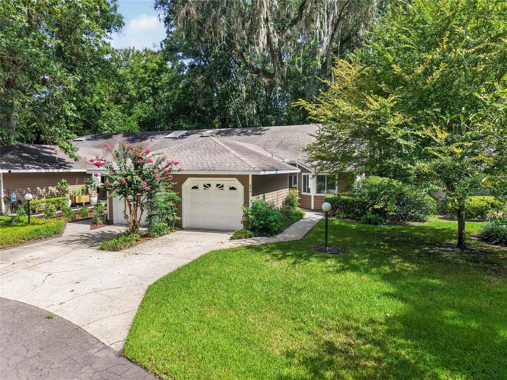 A brown house with a two-car garage and a concrete driveway surrounded by trees — 854 SW 51ST WAY, GAINESVILLE, FL