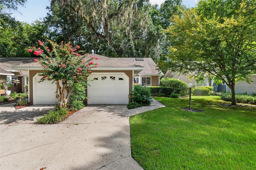 A tan house with a two-car garage and a blooming crape myrtle tree in front — 854 SW 51ST WAY, GAINESVILLE, FL