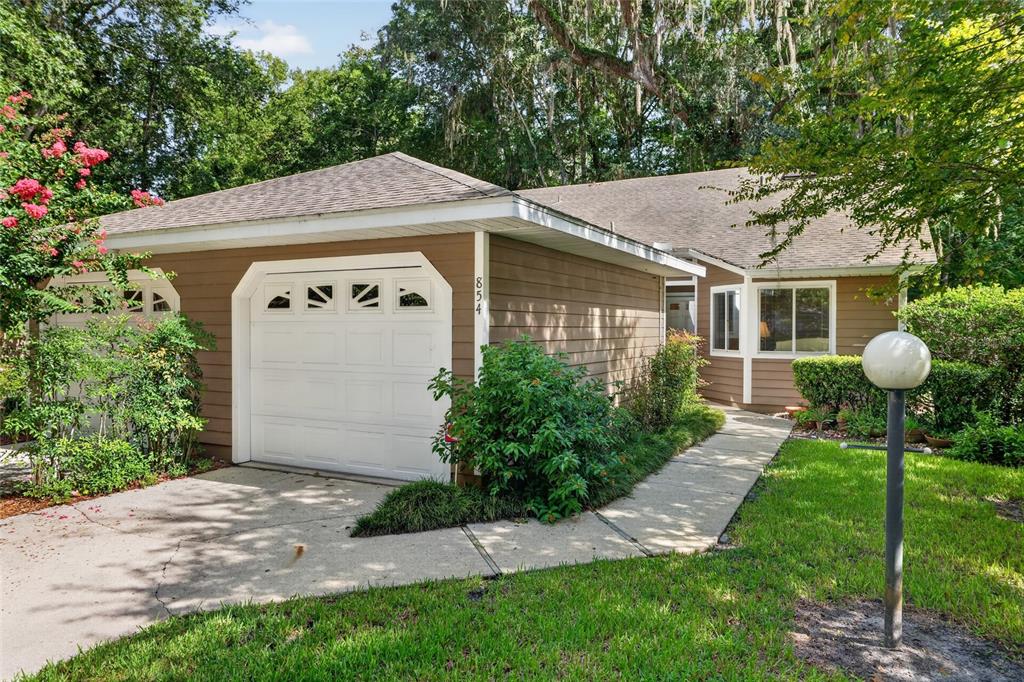 A single-story house with brown siding, a white garage door, and a concrete walkway — 854 SW 51ST WAY, GAINESVILLE, FL