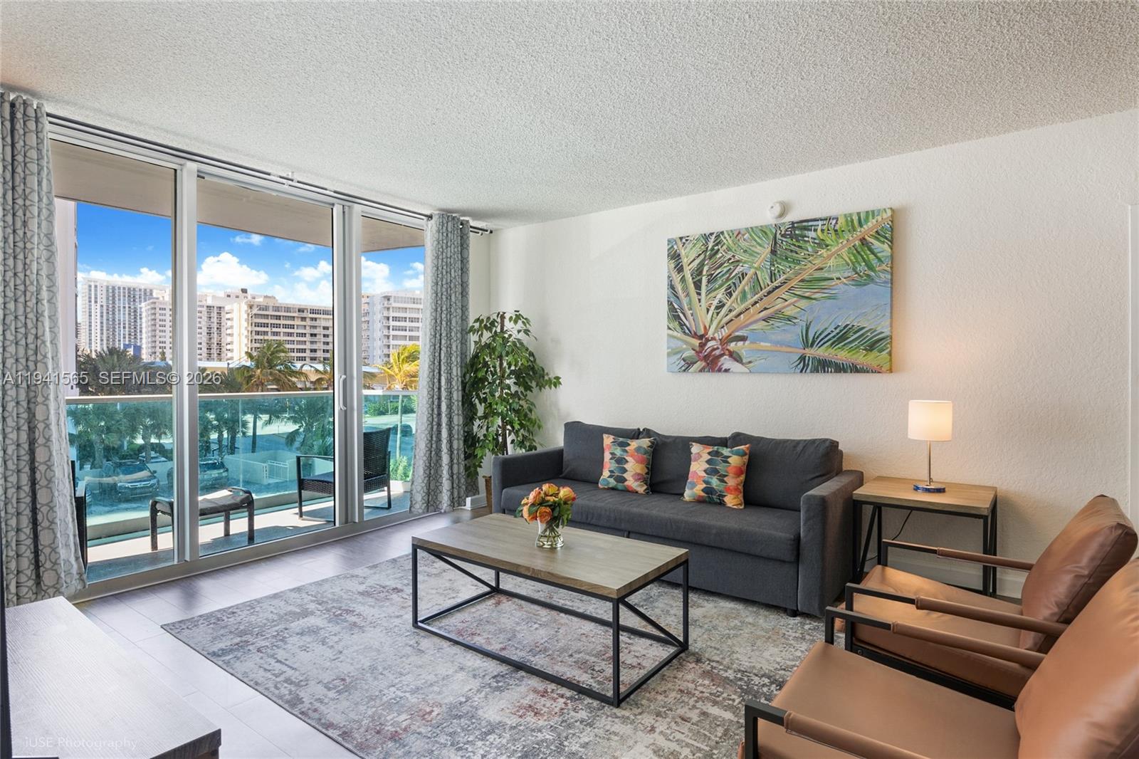 A living room features a dark sofa, two leather chairs, and a balcony with city views — 4001 S Ocean Dr # 3B, Hollywood FL 33019, HOLLYWOOD, FL