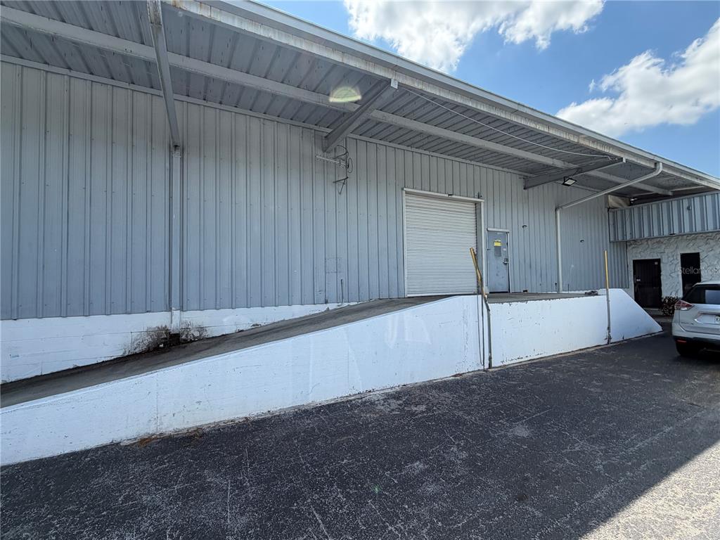 An exterior view of a warehouse building featuring a concrete loading ramp and roll-up door — 510 N TURKEY CREEK ROAD, PLANT CITY, FL