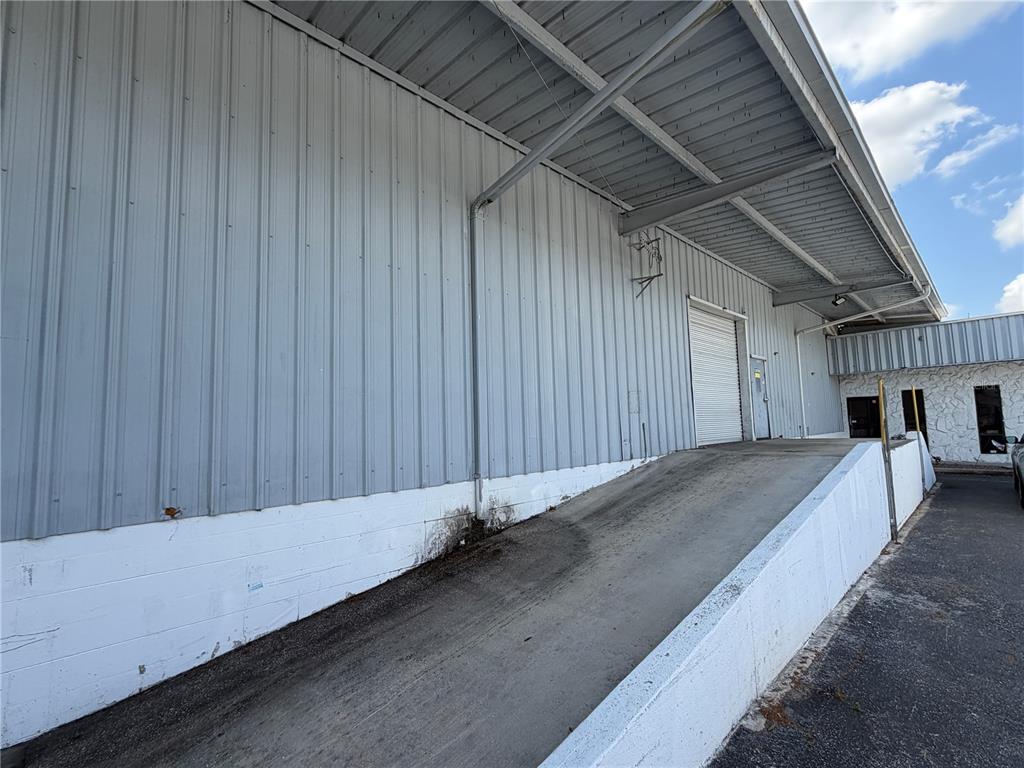 A concrete loading ramp leads to a roll-up door on a metal-sided industrial building — 510 N TURKEY CREEK ROAD, PLANT CITY, FL