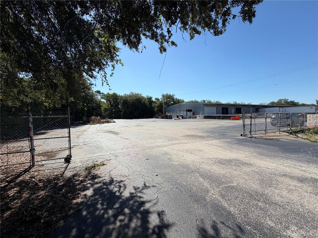 A large, paved outdoor lot is enclosed by chain-link fencing near a warehouse building — 510 N TURKEY CREEK ROAD, PLANT CITY, FL