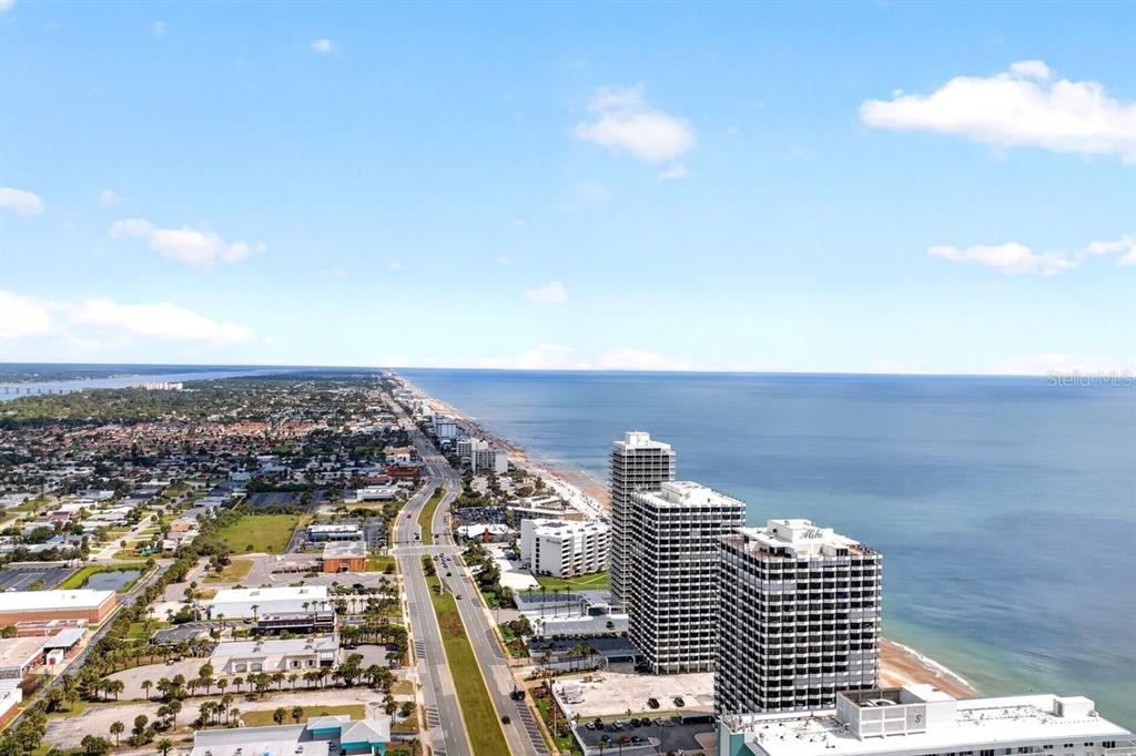 An aerial view shows a coastal highway running alongside high-rise buildings and the ocean — 2900 N ATLANTIC AVENUE UNIT 1006, DAYTONA BEACH, FL