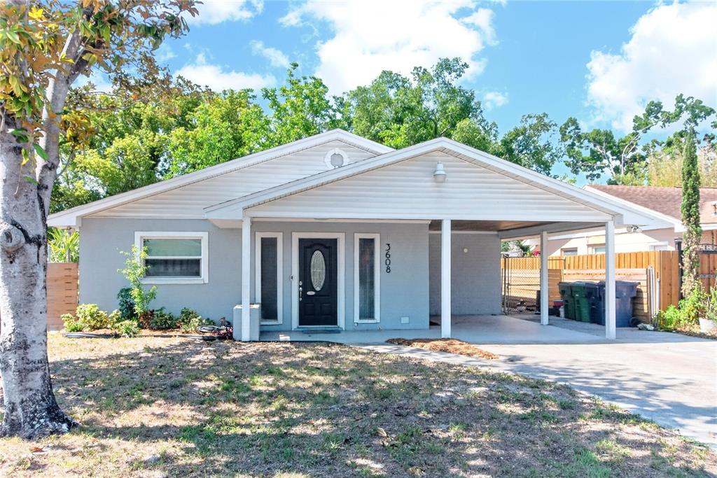 A single-story house with light gray siding, a black front door, and an attached carport — 3608 W CARMEN STREET, TAMPA, FL