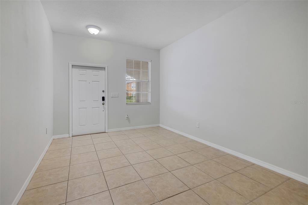 An empty room with light-colored walls, tiled flooring, a white door, and a window — 10975 SAVANNAH LANDING CIRCLE, ORLANDO, FL