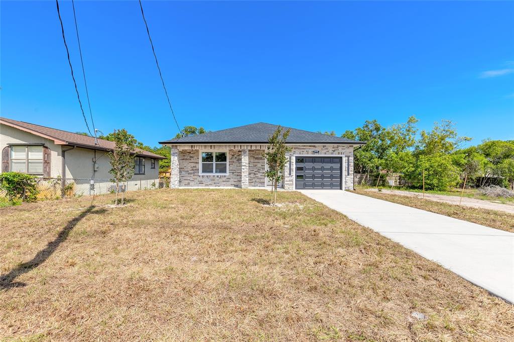 A single-story house with a stone facade, a dark garage door, and a concrete driveway — 1991 CEDAR STREET, DAYTONA BEACH, FL