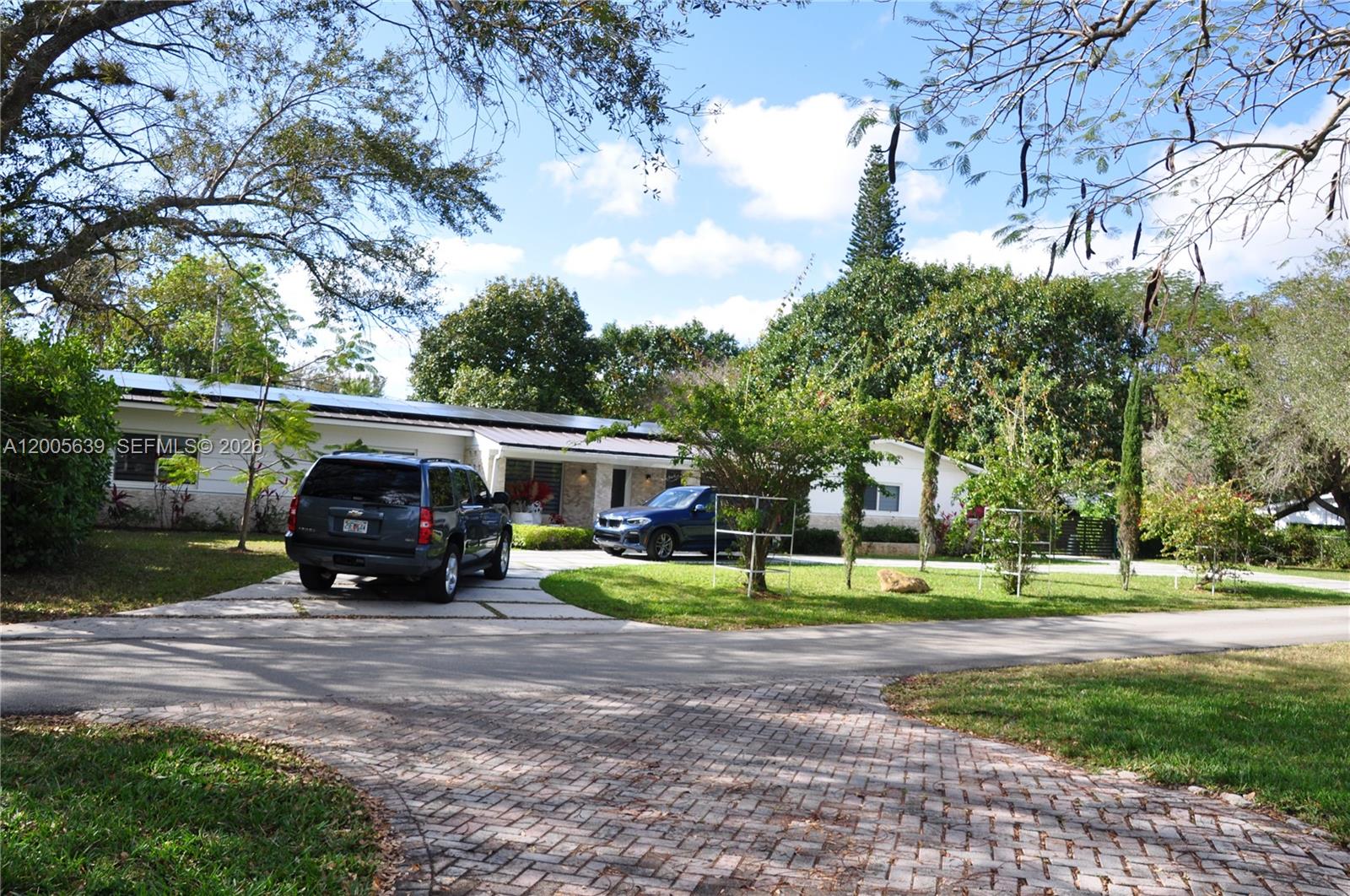 A single-story house with a paved driveway, two parked cars, and mature trees — 7400 SW 116th St, Pinecrest FL 33156, PINECREST, FL