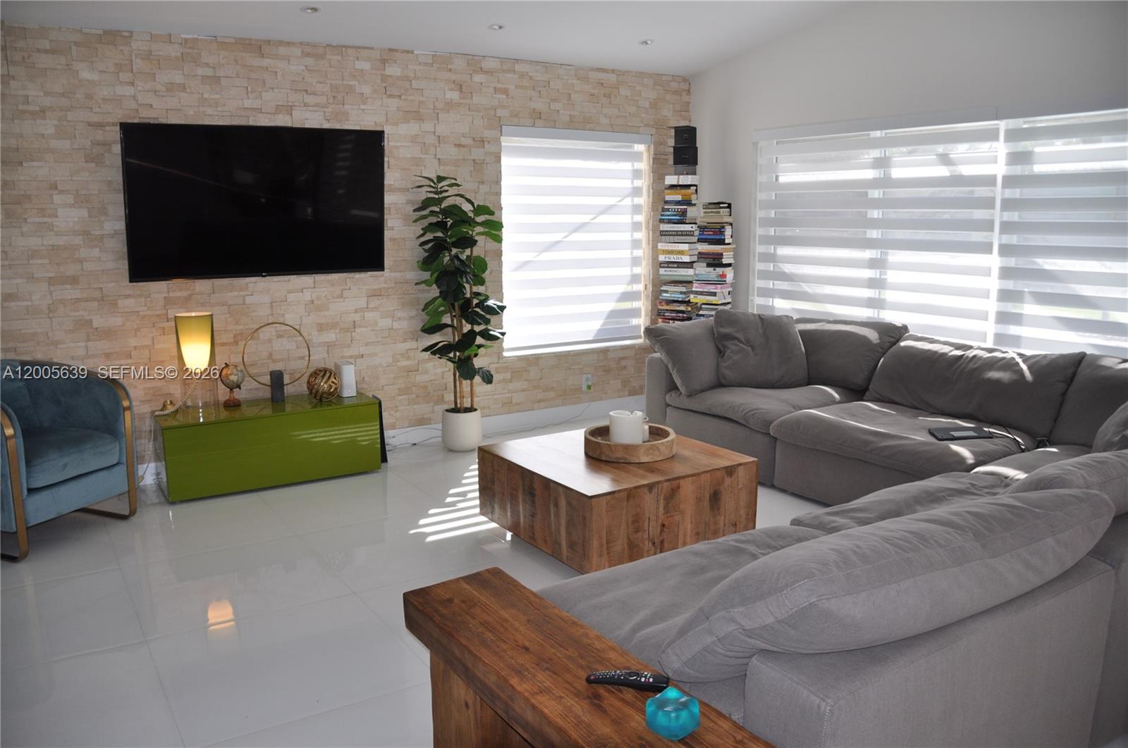 A living room features a stone accent wall, a large sectional sofa, and tile flooring — 7400 SW 116th St, Pinecrest FL 33156, PINECREST, FL