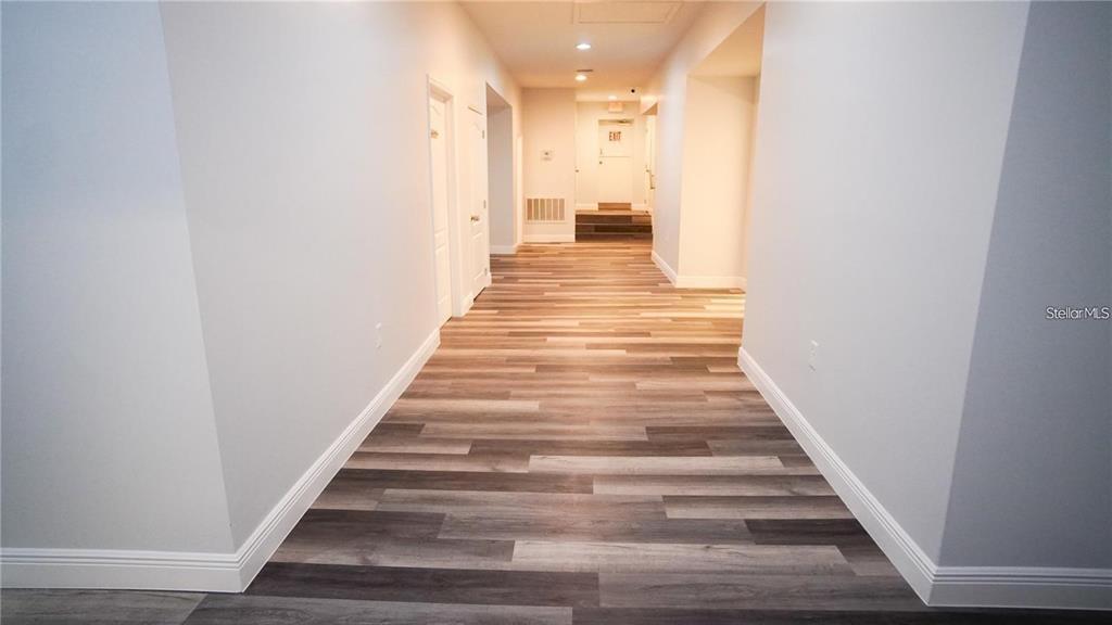 A long hallway features light gray walls and wood-look plank flooring — 103 BROADWAY UNIT 204, KISSIMMEE, FL