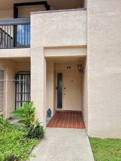 The exterior of a residential building features a tan stucco facade and a tiled entryway — 2355 SW 15th St # 73, Deerfield Beach FL 33442, DEERFIELD BEACH, FL