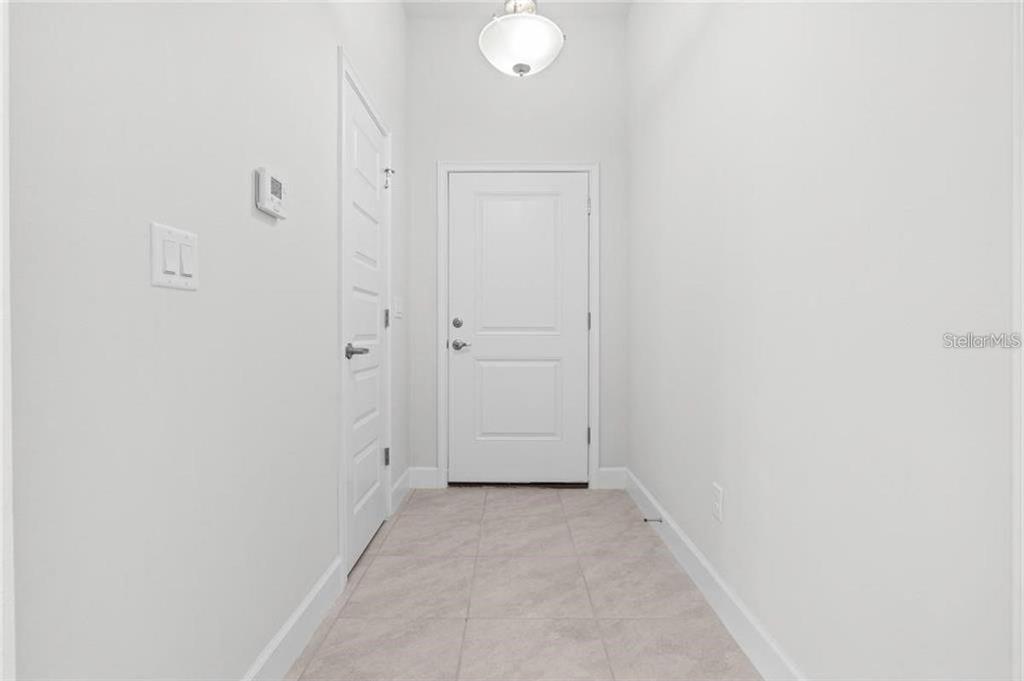 An entryway features light-colored tile flooring, white walls, a white door, and a ceiling light — 4 SERIEMA COURT, PALM COAST, FL