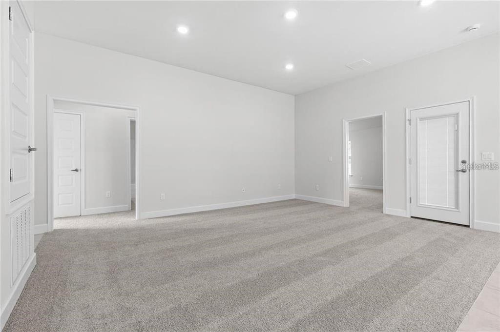 A carpeted room with white walls, recessed lighting, and several interior doors — 4 SERIEMA COURT, PALM COAST, FL