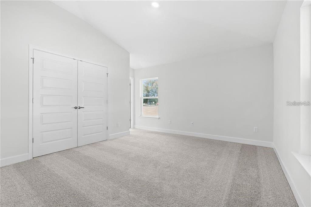 A bright, empty bedroom features white walls, gray carpeting, and a double-door closet — 4 SERIEMA COURT, PALM COAST, FL