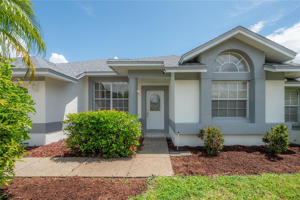 A single-story house with a gray roof, white stucco walls, and a manicured front lawn — 15121 HEATHRIDGE DRIVE, TAMPA, FL