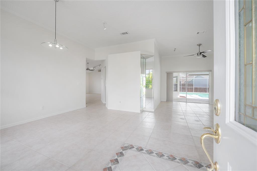An open-concept living area features white walls, tile flooring, a dining light, and pool views — 15121 HEATHRIDGE DRIVE, TAMPA, FL