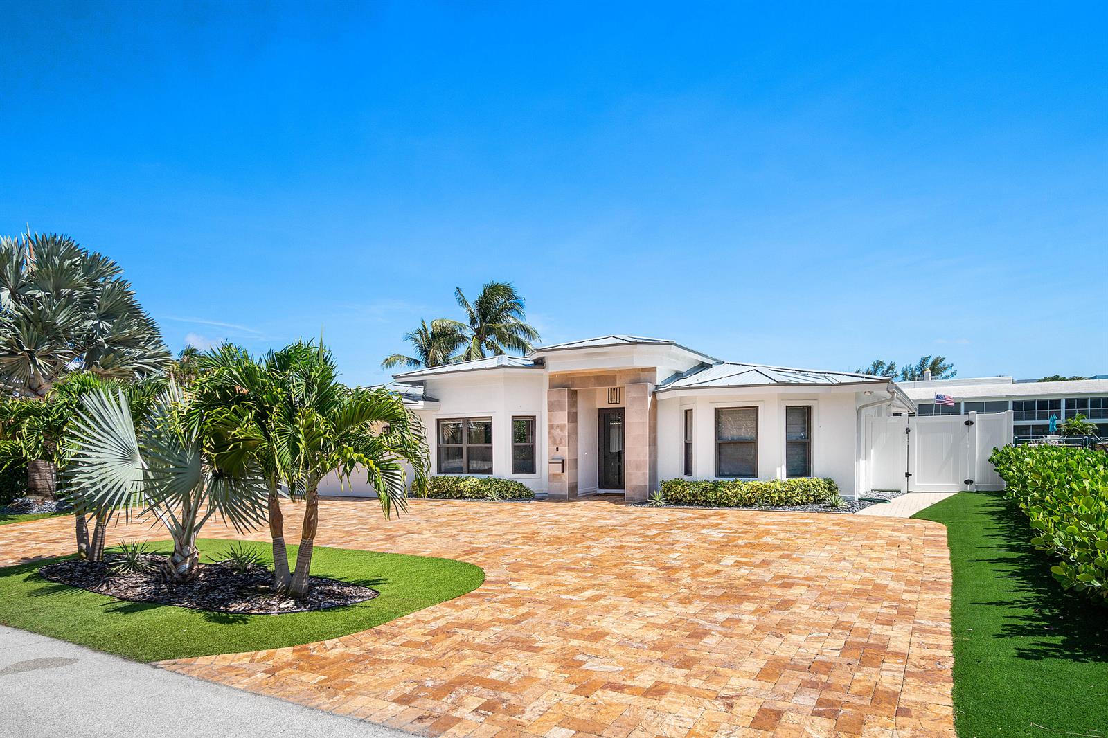 A white single-story house features a stone entryway, a large paver driveway, and palm trees — 680 NE Harbour Drive, Boca Raton FL 33431, BOCA RATON, FL