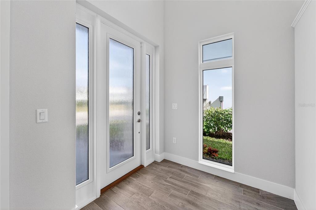 An entryway with a white front door, frosted glass panels, and a tall vertical window — 5917 CAT CLAW LANE, BRADENTON, FL