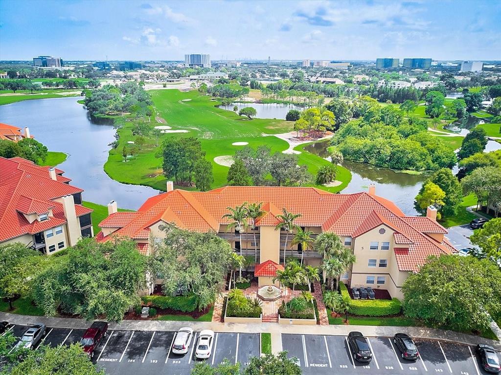 An aerial view shows a multi-story apartment building with a red tile roof near a golf course — 2400 FEATHER SOUND DRIVE UNIT 534, CLEARWATER, FL