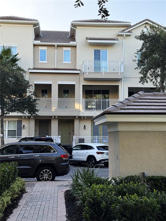 A multi-story townhouse exterior features balconies, a paved walkway, and parked cars in front — 1487 LAKE GEORGE DRIVE, LAKE MARY, FL