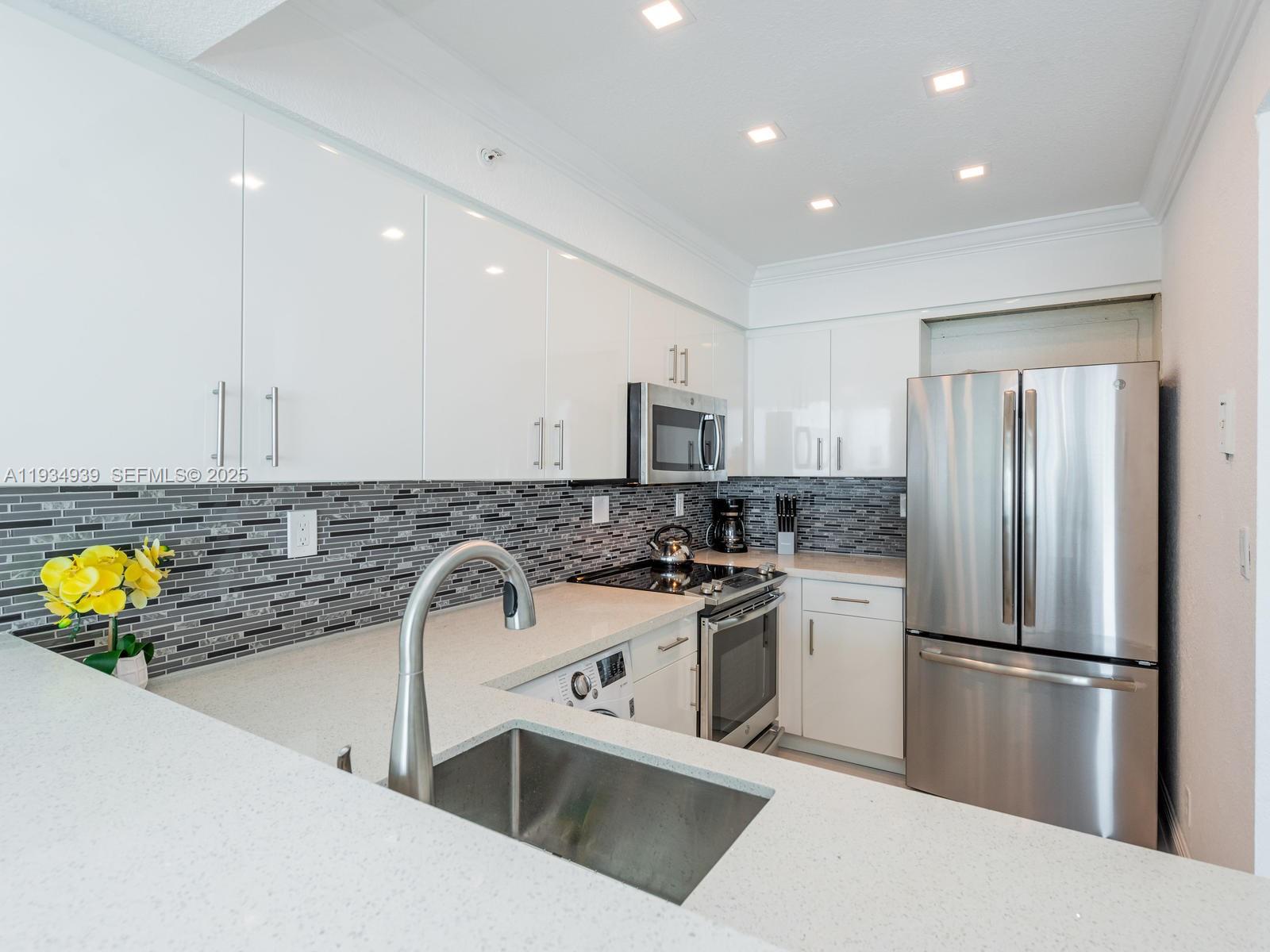 A modern kitchen features white cabinets, stainless steel appliances, and a gray tiled backsplash — 2501 S Ocean Dr, Hollywood FL 33019, HOLLYWOOD, FL