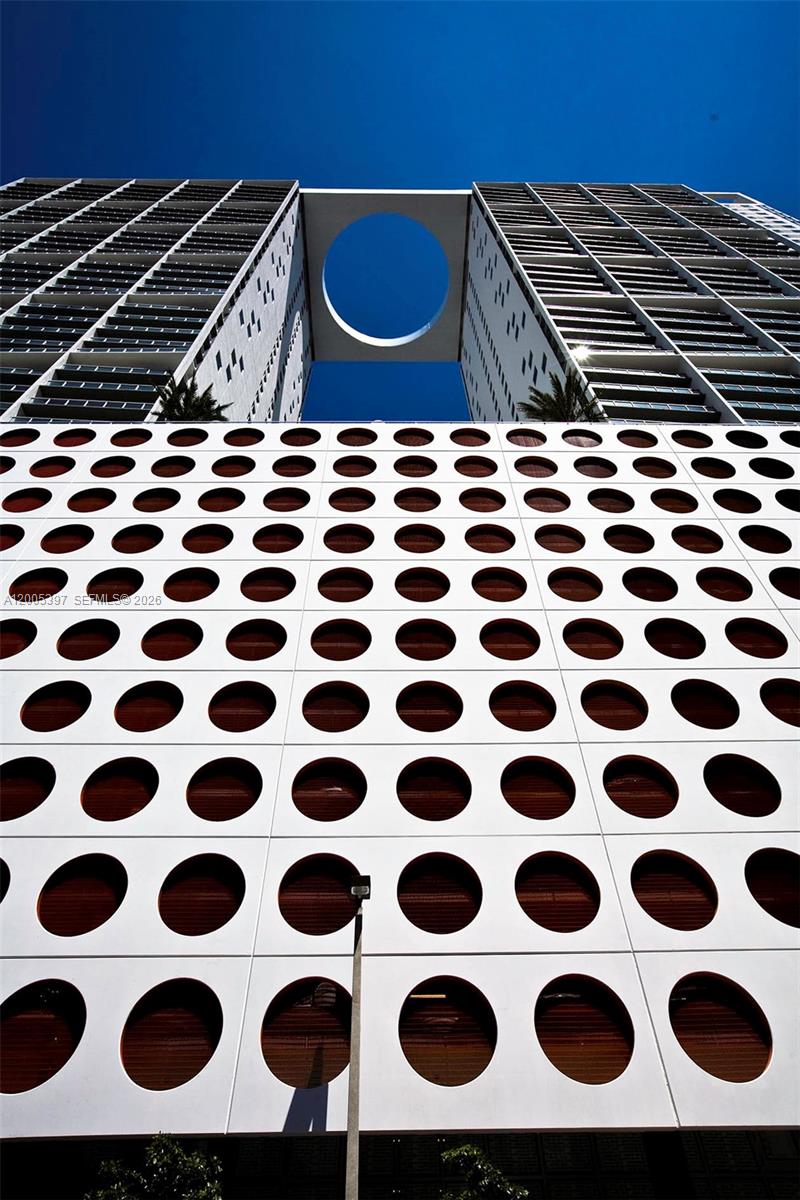 A low-angle view of a modern building facade featuring a grid of circular cutouts — 500 Brickell Ave # 1405, Miami FL 33131, MIAMI, FL