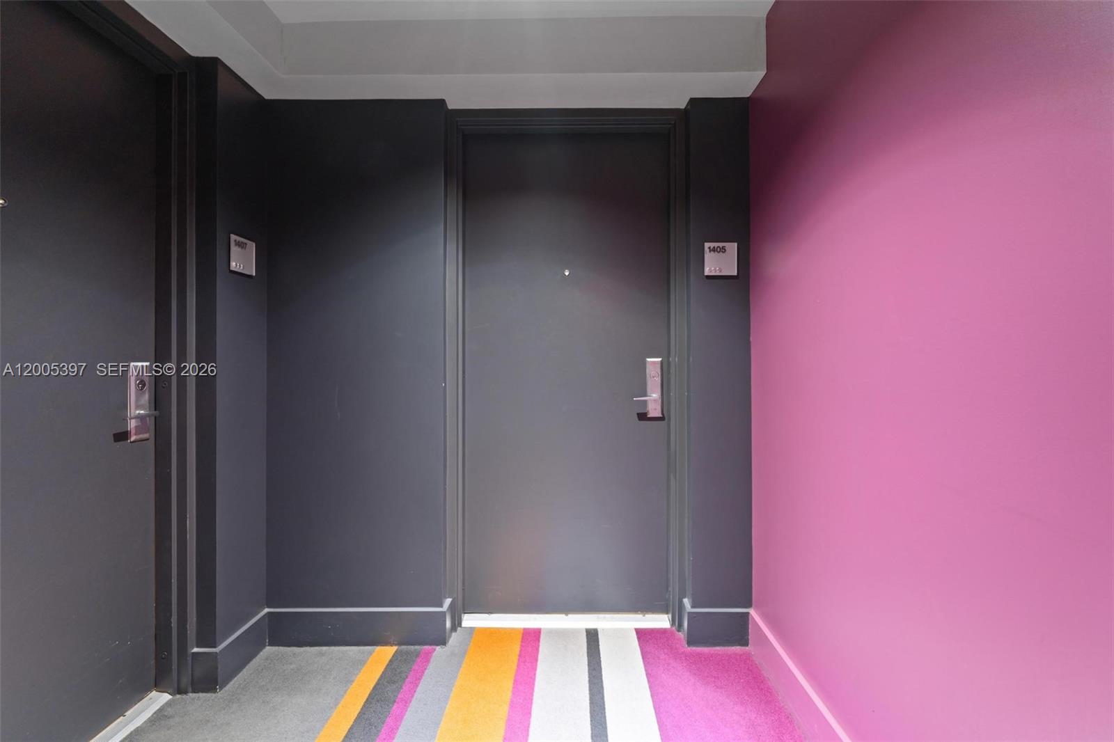 A hallway features two dark gray doors, a bright pink wall, and striped carpet flooring — 500 Brickell Ave # 1405, Miami FL 33131, MIAMI, FL