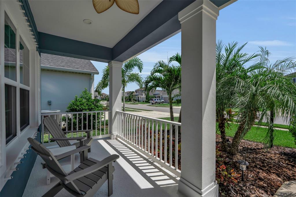 A covered front porch features two gray chairs, white railings, and views of a neighborhood — 3321 WOODMONT DRIVE, PARRISH, FL