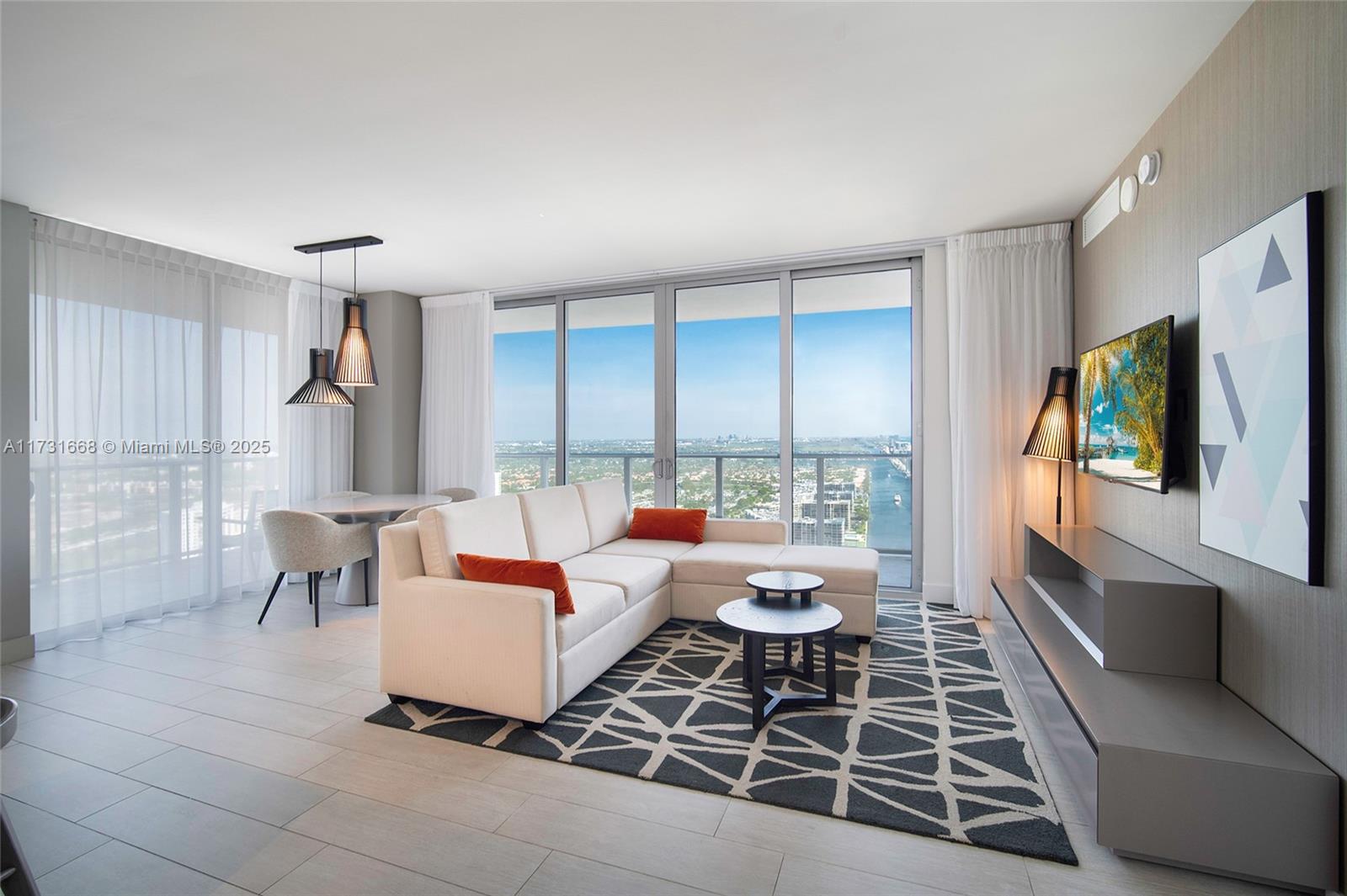 A modern living room features a white sectional sofa, patterned area rug, and floor-to-ceiling windows — 4010 S Ocean Dr # T3502, Hollywood FL 33019, HOLLYWOOD, FL