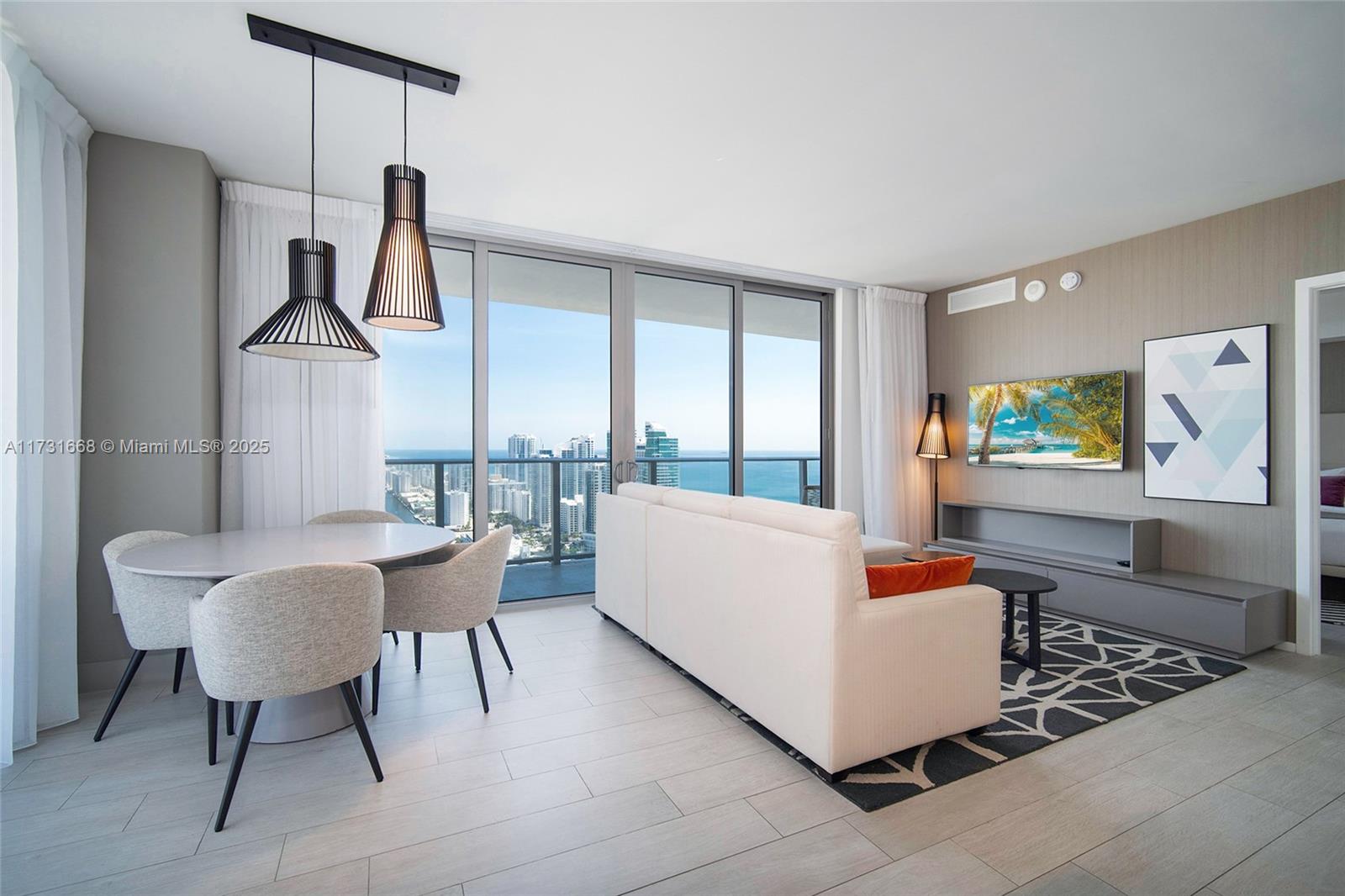 A modern living and dining area features a white sofa, round table, and ocean views — 4010 S Ocean Dr # T3502, Hollywood FL 33019, HOLLYWOOD, FL