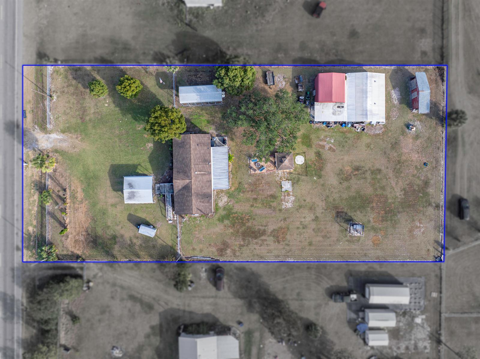 This aerial view shows a residential property with a house, several outbuildings, and trees — 11404 Lithia Pinecrest Road, FL 33547, FL