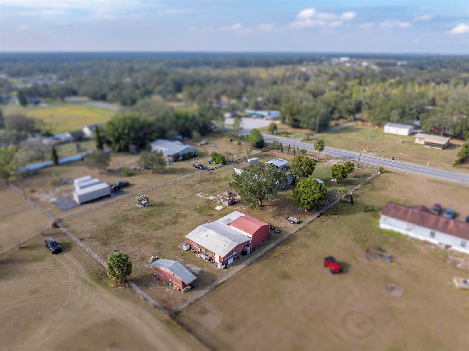 An aerial view shows a rural property with a house, outbuildings, and fenced yard — 11404 Lithia Pinecrest Road, FL 33547, FL