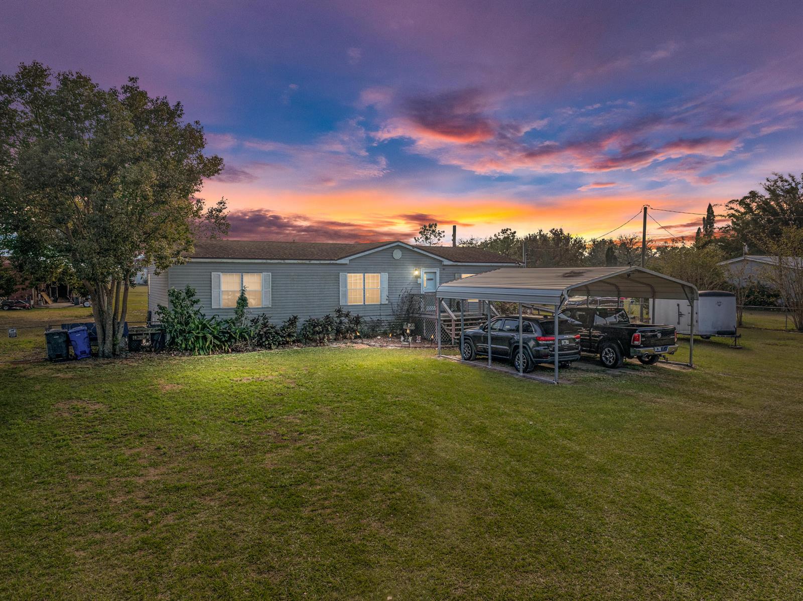 A single-story house with a metal carport and two parked vehicles under a sunset sky — 11404 Lithia Pinecrest Road, FL 33547, FL