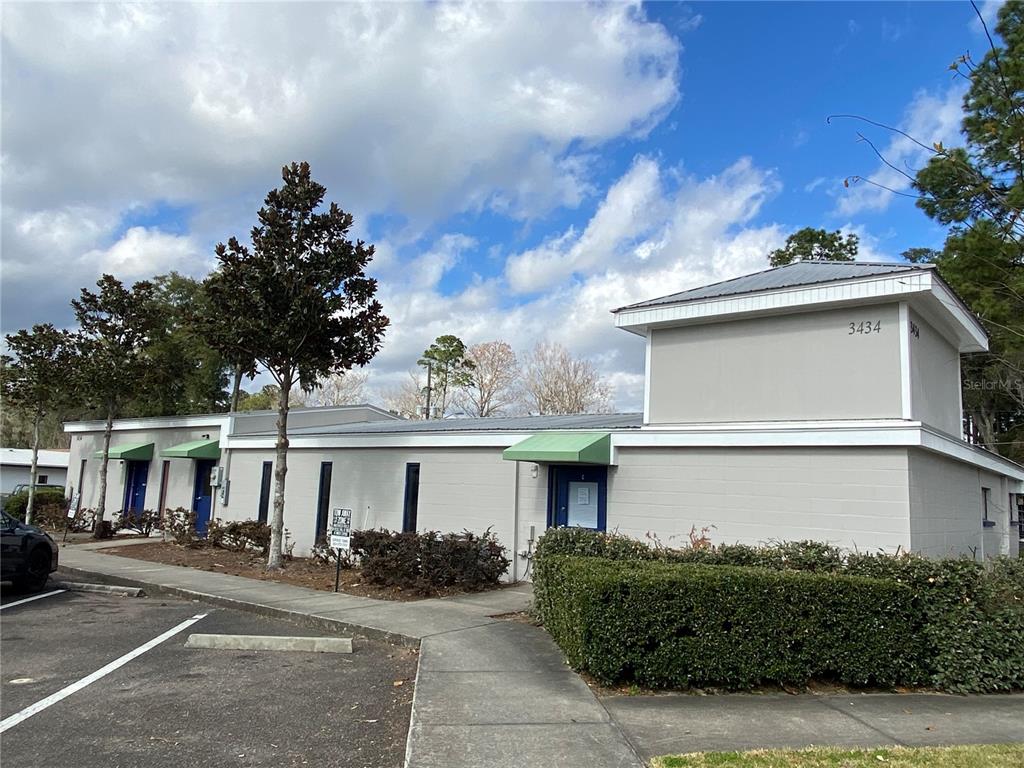 A single-story commercial building with a gray exterior, green awnings, and a prominent corner tower — 3434 SW 24TH AVENUE UNIT B, GAINESVILLE, FL