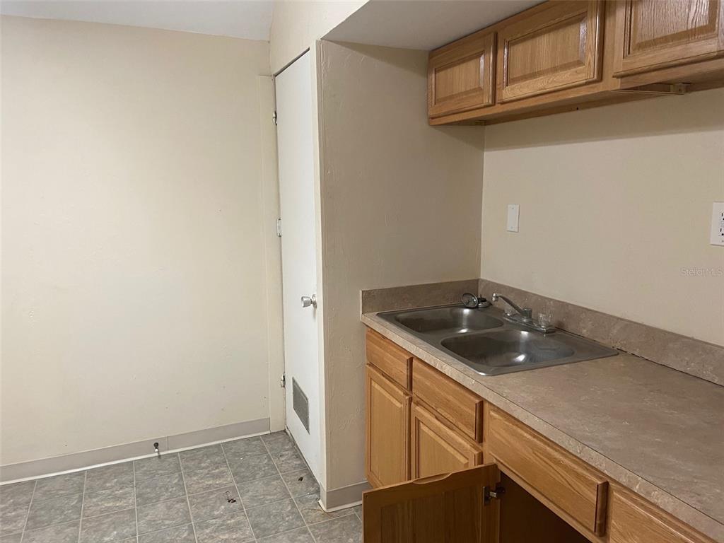 A kitchen features light-colored walls, wood cabinets, a double-basin sink, and gray tile flooring — 3434 SW 24TH AVENUE UNIT B, GAINESVILLE, FL