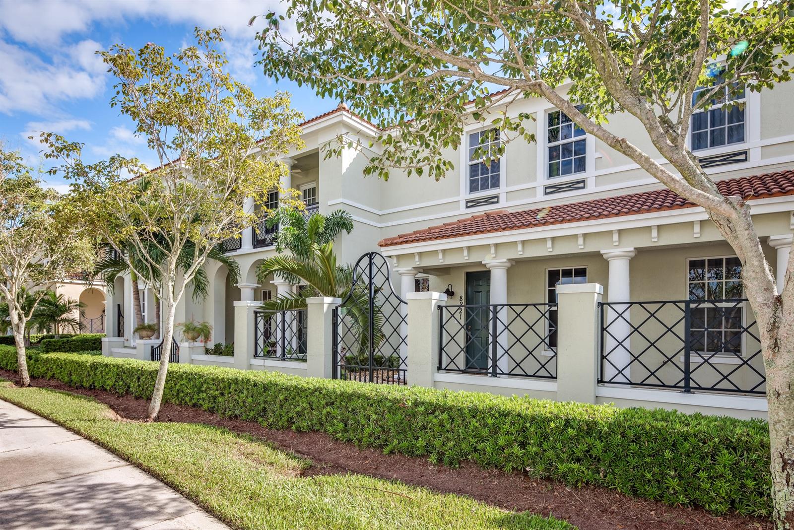 A two-story townhouse exterior features a gated front patio, columns, and a manicured hedge — 8221 NW 8th Way, Boca Raton FL 33487, BOCA RATON, FL