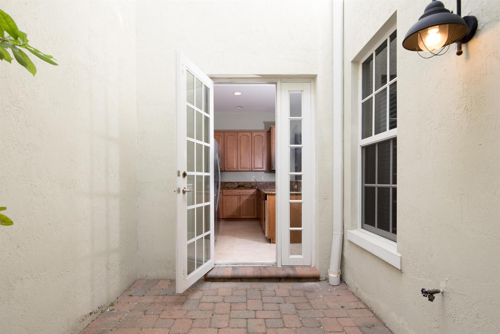 A view from a brick patio through an open French door into a kitchen — 8221 NW 8th Way, Boca Raton FL 33487, BOCA RATON, FL