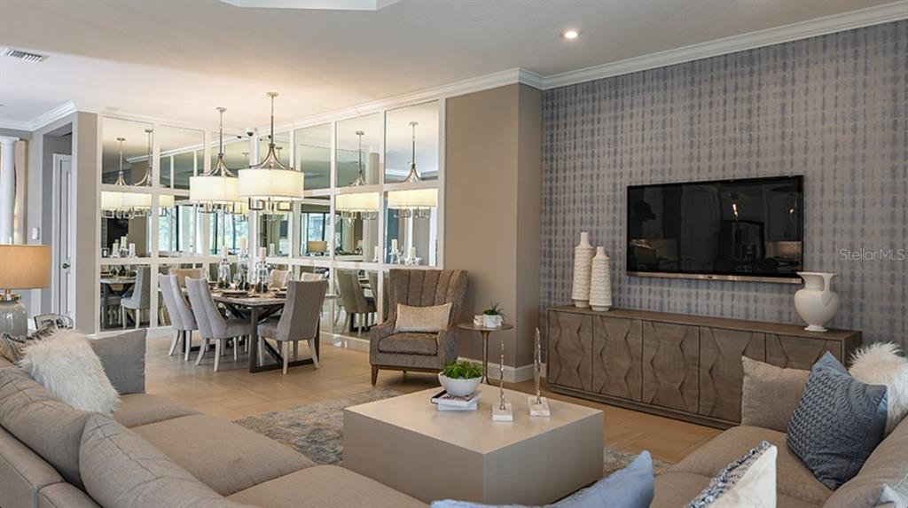 A living room features a large sectional sofa, a coffee table, and a mirrored dining area — 29680 IMPERATI BOULEVARD, WESLEY CHAPEL, FL