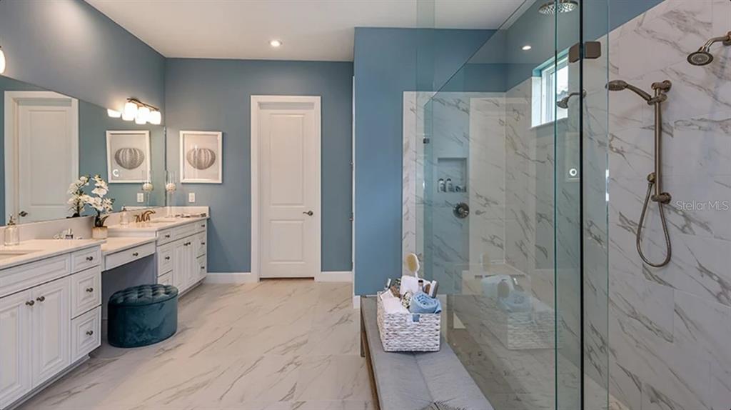 A bathroom with blue walls, white cabinetry, a marble-tiled floor, and a glass-enclosed shower — 29680 IMPERATI BOULEVARD, WESLEY CHAPEL, FL