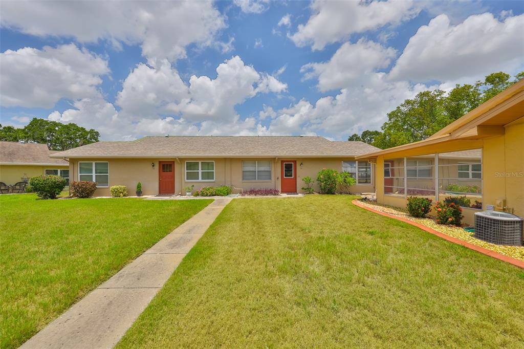 A view of the exterior of a single-story duplex with two red front doors — 1904 CANTERBURY LANE UNIT 18, SUN CITY CENTER, FL