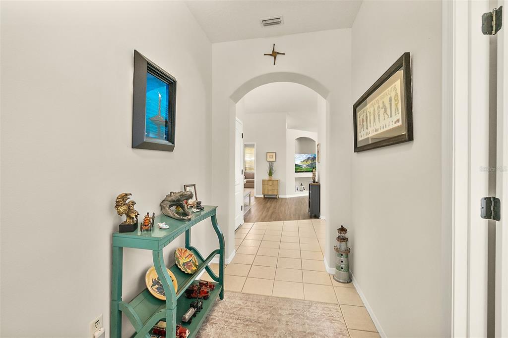 A tiled entryway features a teal console table, wall art, and an arched doorway — 17 ARBOR TRACE UNIT 17, PALM COAST, FL