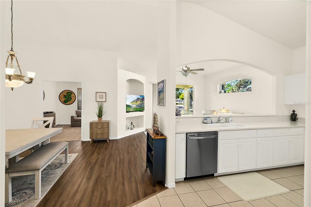A kitchen with white cabinets and a dishwasher opens to a dining and living area — 17 ARBOR TRACE UNIT 17, PALM COAST, FL