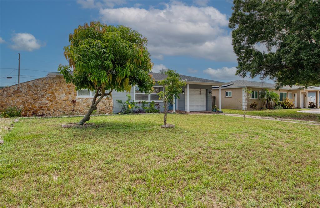 A single-story house with a stone facade, gray siding, and a front lawn with trees — 5213 97TH WAY N, ST PETERSBURG, FL