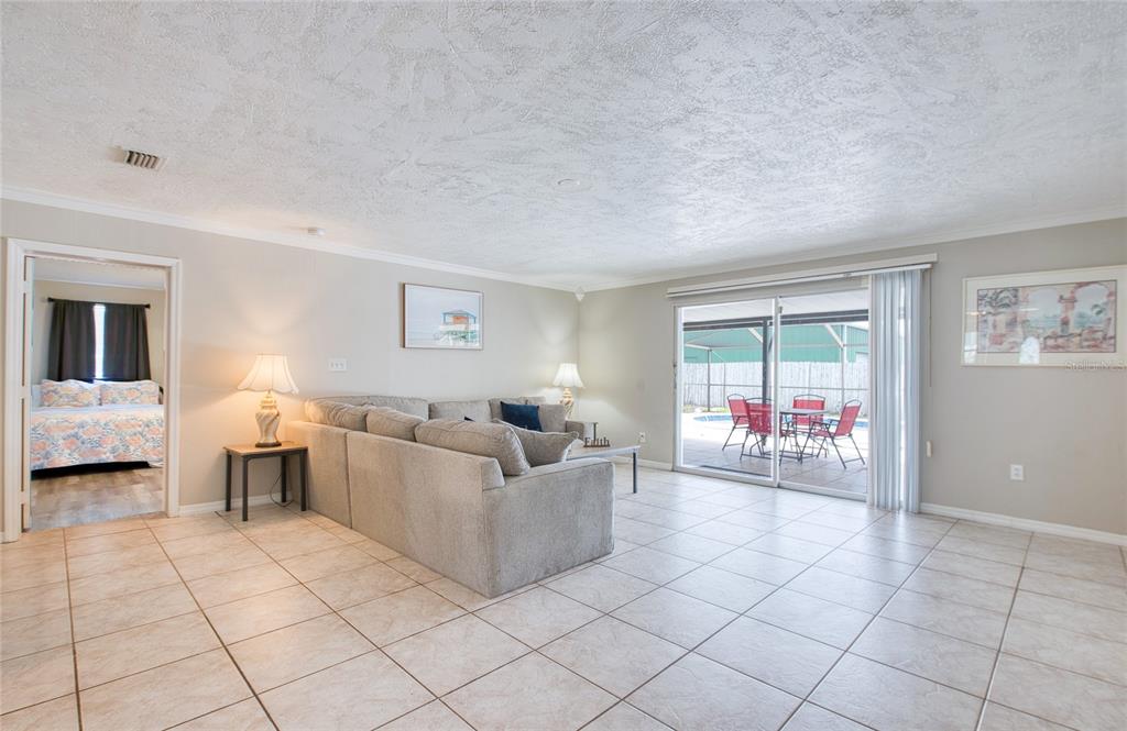A living room with tile floors, a sectional sofa, and sliding glass doors to a patio — 5213 97TH WAY N, ST PETERSBURG, FL