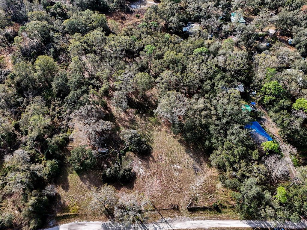 An aerial view shows a partially cleared, wooded lot bordering a paved road — 40550 SUTORUS ROAD, ZEPHYRHILLS, FL