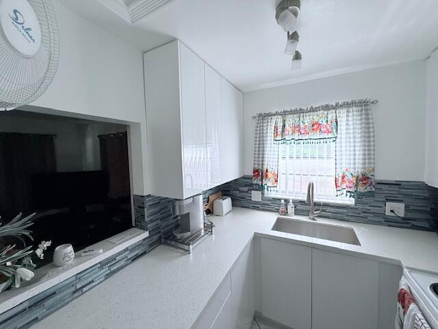 A kitchen features white cabinets, quartz countertops, a stainless steel sink, and blue tile backsplash — 41 Upminster B Crescent # B, Deerfield Beach FL 33442, DEERFIELD BEACH, FL