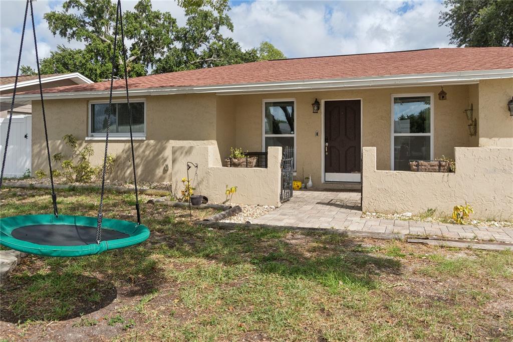 A single-story house with a tan stucco exterior, a red roof, and a front patio — 7528 SCOTTIE DRIVE, PORT RICHEY, FL