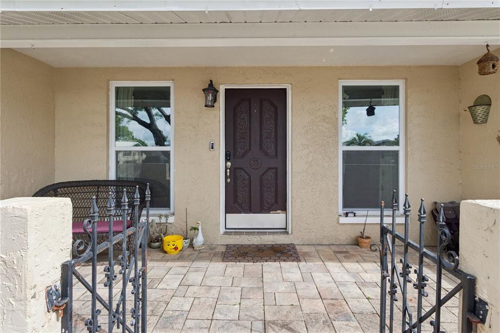 A front porch features a paved floor, a dark door, and a black metal gate — 7528 SCOTTIE DRIVE, PORT RICHEY, FL